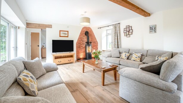 Ein Wohnzimmer mit Kamin, einer Sofagarnitur, einem Fernseher und einem Couchtisch aus Holz.