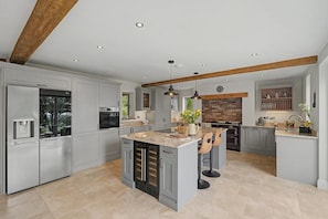 A spacious kitchen with grey cabinets, a central island, and a wooden ceiling beam.