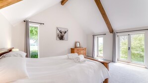 Ein Schlafzimmer mit einem großen Bett, einem Holzkopfende, einem Nachttisch, einer Kommode und einem gerahmten Bild an der Wand.