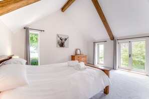 Een slaapkamer met een groot bed, houten hoofdeinde, een nachtkastje, een kaptafel en een lijst met een afbeelding aan de muur.