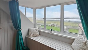 Ein Zimmer mit integriertem Sitzplatz an einem Fenster mit Blick auf eine grüne Landschaft.