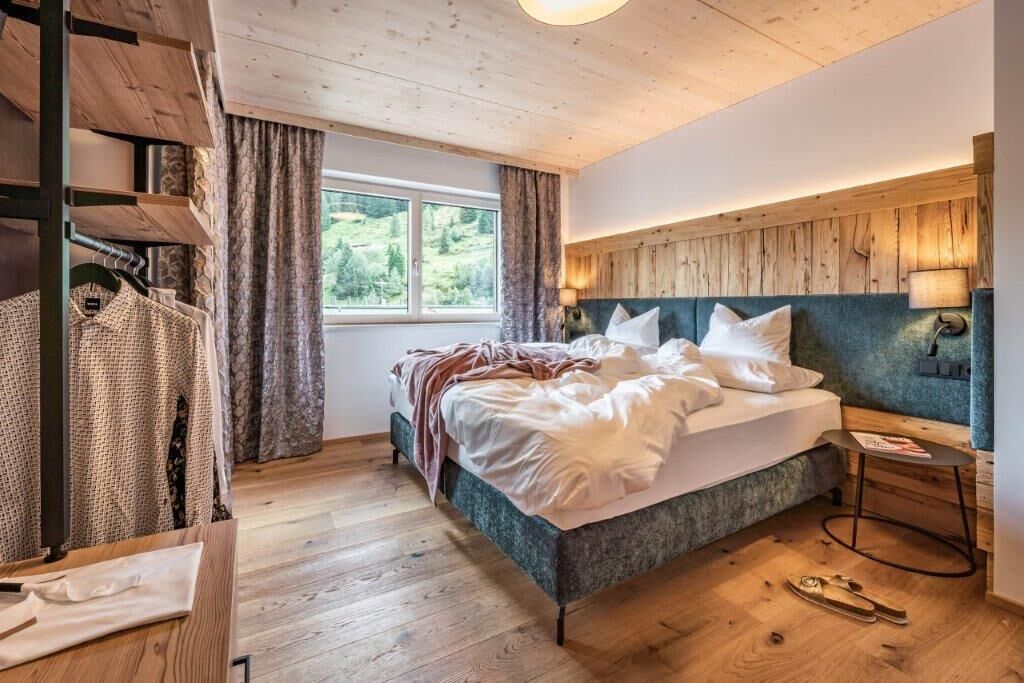 Ein Schlafzimmer mit einem Bett, einem Fenster, einer Holzbalkendecke und einem Nachttisch.