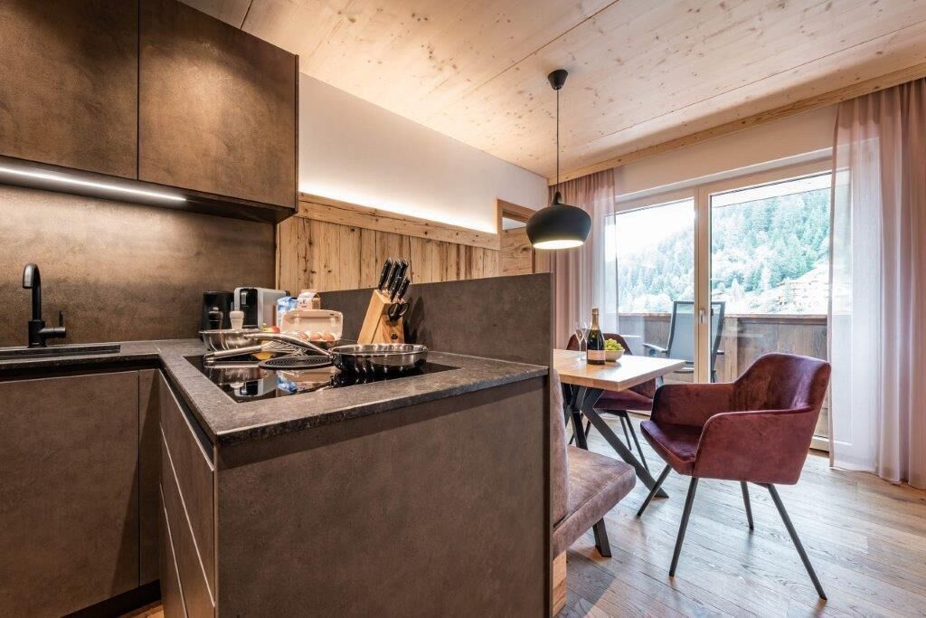 Et moderne køkken med en central ø, træskabe og et spiseområde med et bord og stole.