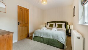 A neatly arranged bedroom with a bed, a wooden door, a radiator, and a window with curtains. - 2 Bed in Holkham (oc-c34779) (Holkham)