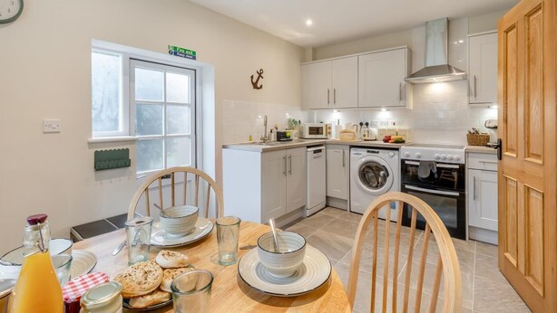 A compact kitchen with a dining area, a washing machine, a microwave, and a stove. - 2 Bed in Holkham (oc-c34779) (Holkham)