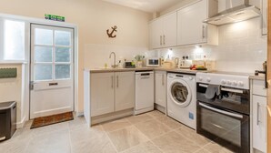 A modern kitchen with a dishwasher, washing machine, oven, and a microwave. - 2 Bed in Holkham (oc-c34779) (Holkham)
