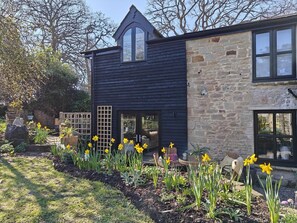 A modern house with a dark exterior, stone walls, and a garden with daffodils. - 3 Bed in Ellwood (oc-t35963) (Ellwood)