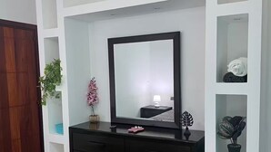 A bedroom with a large bed, a dresser with drawers, a mirror, and built-in shelving with plants. - Lovely apt with 2 BR and Two balcony with sea view (La Romana)