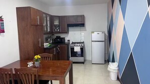 A compact kitchen with wooden cabinets, a gas stove, a microwave, and a refrigerator. - Lovely apt with 2 BR and Two balcony with sea view (La Romana)