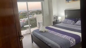 A bedroom with a bed, a nightstand, a potted plant, and a painting on the wall. - Lovely apt with 2 BR and Two balcony with sea view (La Romana)