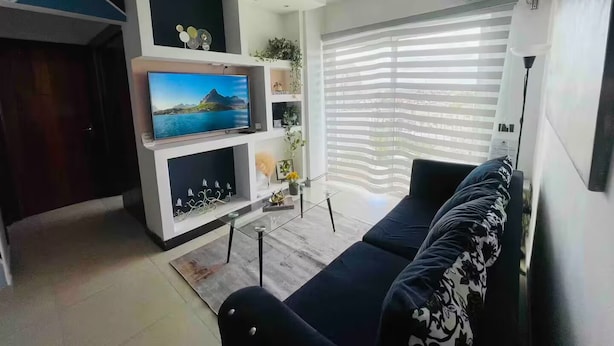 A modern living room with a flat-screen TV, a sofa, and a dining area. - Lovely apt with 2 BR and Two balcony with sea view (La Romana)