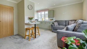 A modern kitchen with a dining area, a grey sofa, and a red table.
