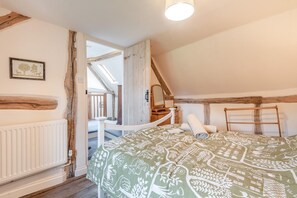 A bedroom with a sloped ceiling, wooden beams, a bed with patterned bedding, a bedside table, a mirror, and a view of a balcony. - 4 Bed in Shrawley (oc-s34861) (Shrawley)