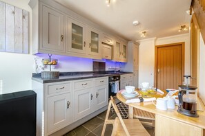 A modern kitchen with light-colored cabinets, a built-in oven, and a breakfast setup on the counter.