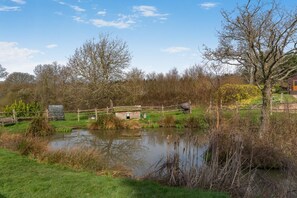 A pond with a wooden structure, surrounded by trees and a grassy area.