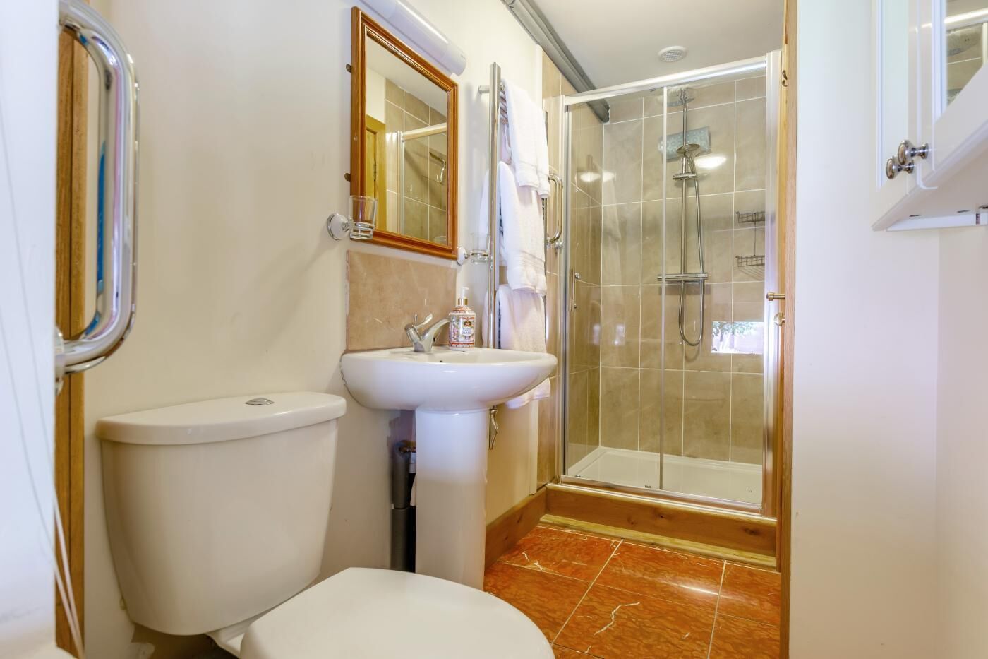 Een badkamer met toilet, wastafel, spiegel en douchecabine.