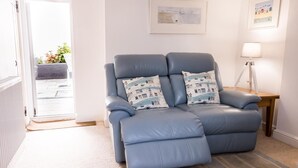 A room with a blue leather recliner, a side table with a lamp, and a framed picture on the wall. - 2 Bed in Shaldon (oc-t36353) (Shaldon)