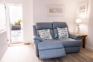 A room with a blue leather recliner, a side table with a lamp, and a framed picture on the wall. - 2 Bed in Shaldon (oc-t36353) (Shaldon)
