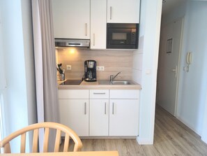 A compact kitchenette with a microwave, coffee maker, and sink. - Perfekt fur Zwei - Moderne Fewo mit Balkon in Sellin (Sellin)