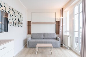Ein modernes Wohnzimmer mit einem grauen Sofa, einem Holztisch und einem an der Wand befestigten abstrakten Kunstwerk.