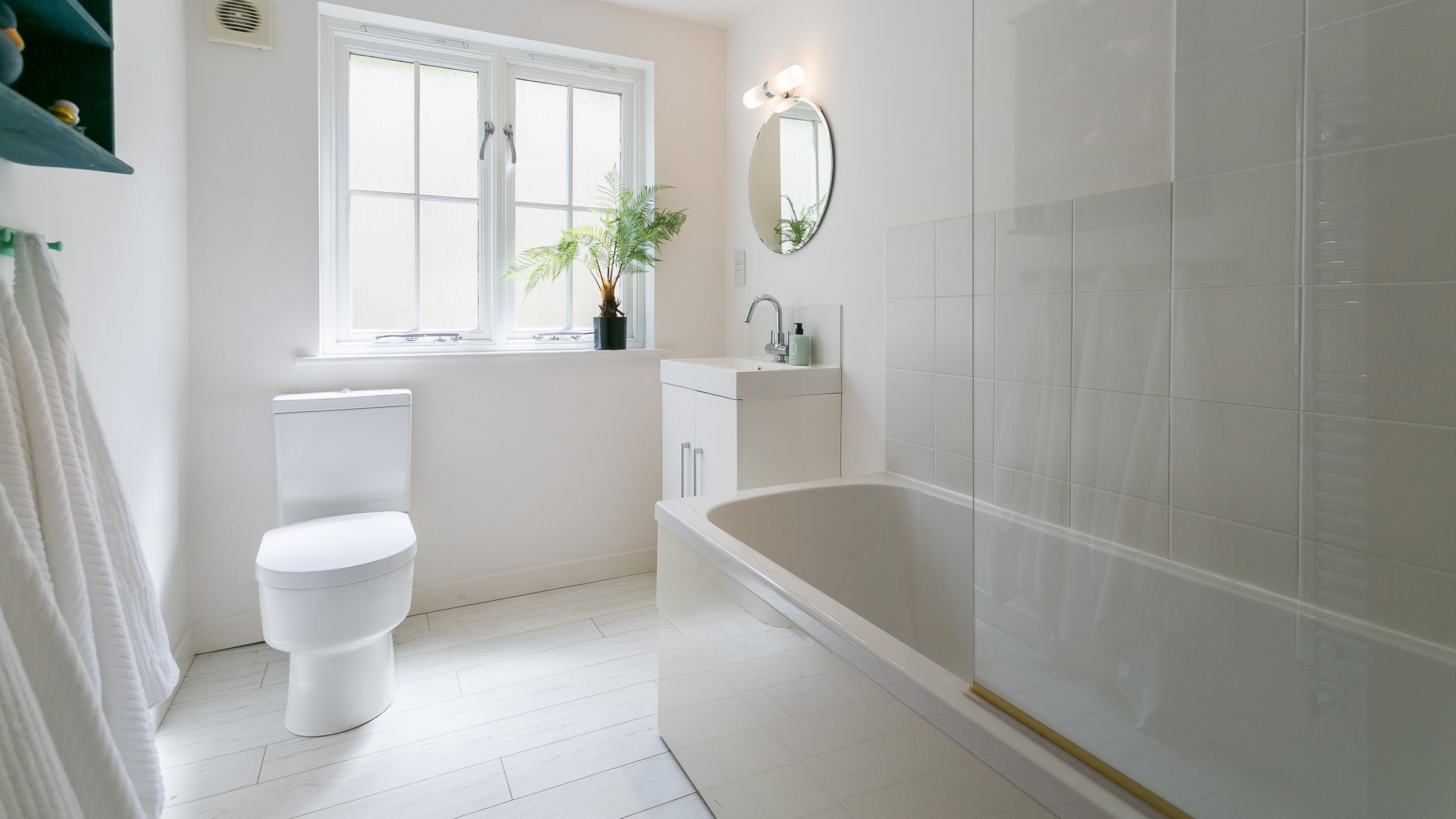 A bathroom with a toilet, sink, bathtub, and a window with a plant.