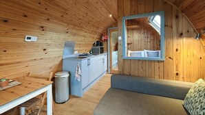 A compact, wooden interior with a kitchenette, a dining area, and a seating area. - 1 Bed in Tyn-y-Groes (oc-g36300) (Ty'n-y-groes)