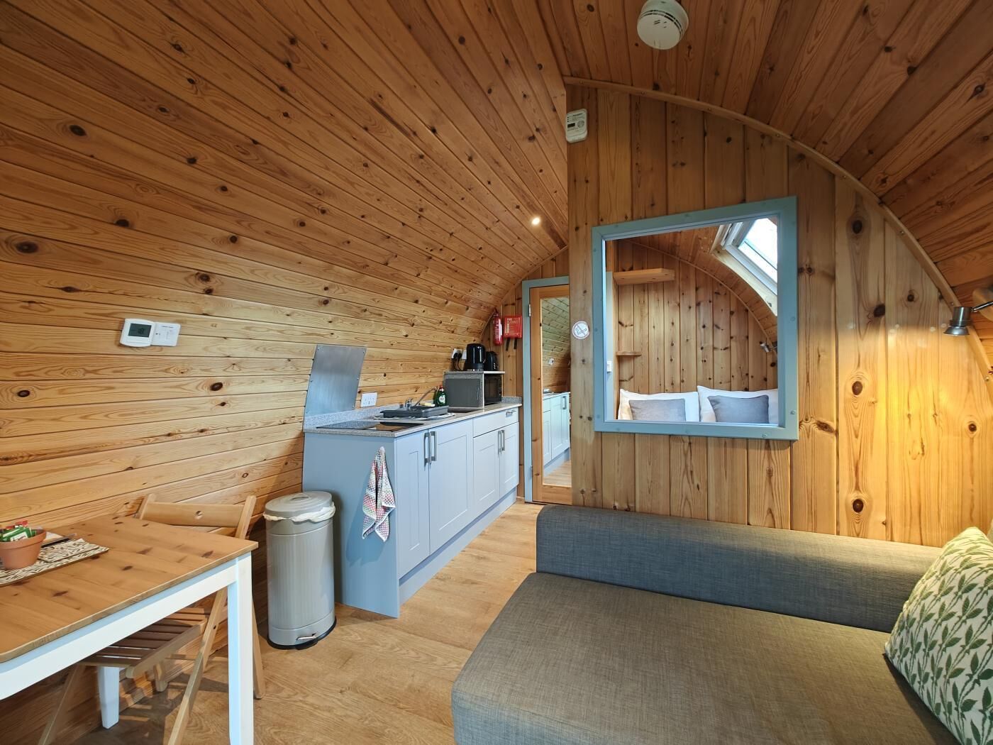 Un intérieur compact en bois comprenant un coin cuisine, un espace repas et un coin salon.