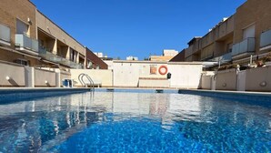 A swimming pool with clear blue water, surrounded by buildings with balconies. - La Mota Beach House with Pool & BBQ (Cubelles)