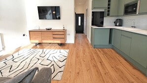 Eine moderne Küche mit Einbauofen, Mikrowelle und Spüle. Es gibt einen Holzschrank und einen Flachbildfernseher an der Wand.