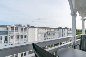 Ein Balkon mit Blick auf weiße Gebäude, einem Tisch und einem Stuhl.