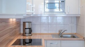 A modern kitchen with a built-in microwave, coffee maker, and stainless steel sink. - Ferienwohnung Nahe Strand und Seebrucke in Sellin (Sellin)