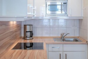 A modern kitchen with a built-in microwave, coffee maker, and stainless steel sink. - Ferienwohnung Nahe Strand und Seebrucke in Sellin (Sellin)