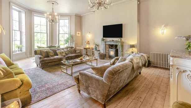 A spacious living room with a fireplace, large windows, and a chandelier. - 4 Bed in Barnstaple (oc-n34877) (Newton Tracey)