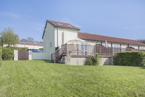 Un immeuble résidentiel à deux étages, doté de fondations en pierre, d’une clôture en bois et d’une pelouse devant.
