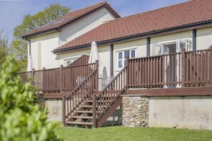 Ein zweistöckiges Gebäude mit Steinuntergrund, einer Holztreppe und einem Balkon mit Holzbalkon.