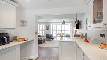 A modern kitchen with white cabinets, a built-in oven, and a dining area with a table and chairs.