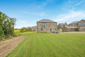 A stone house with a well-maintained lawn and a dirt path. - 2 Bed in Padstow (oc-g34917) (Trevone)