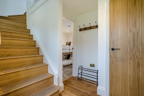 A wooden staircase leading to a room with a bunk bed, a coat rack, and a door. - 2 Bed in Padstow (oc-g34917) (Trevone)