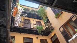 A courtyard with a wooden balcony, potted plants, and a door. - Red Hat Home by Campo de Fiori (Rome)