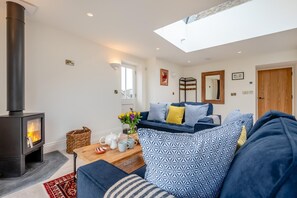 A cozy living room with a fireplace, a sofa set, a coffee table, and a skylight. - 2 Bed in Padstow (oc-f34918) (Trevone)