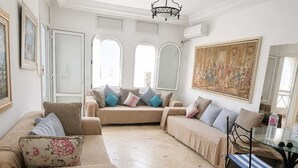 A living room with a sofa set, a glass coffee table, and a painting on the wall. - résidence Nesrine-Hammemet sud (Hammamet)