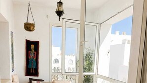 A balcony with a sofa, a small round table, and a metal drying rack. - résidence Nesrine-Hammemet sud (Hammamet)