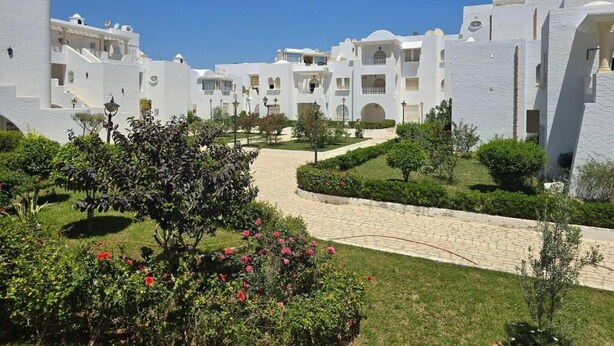 A resort with white buildings, a paved pathway, and landscaped gardens. - résidence Nesrine-Hammemet sud (Hammamet)