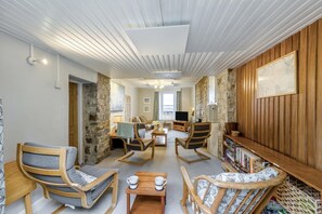 Ein gemütliches Wohnzimmer mit Kamin, bequemen Sitzmöglichkeiten, einem Fernseher und einem Bücherregal.