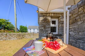 A stone building with a wooden table set for breakfast, including eggs, bread, and fruit. - 1 Bed in Parkmill (oc-t36337) (Parkmill)