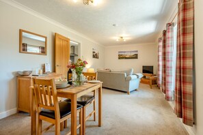 A cozy living room with a sofa, a dining table with chairs, a TV, and a painting on the wall. - 1 Bed in Parkmill (oc-t36337) (Parkmill)
