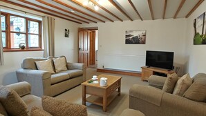 Ein Wohnzimmer mit einer Sofagarnitur, einem Couchtisch, einem Fernseher und einer Heizung.