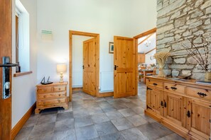 A hallway with wooden doors, a stone wall, and a dining area in the background. - 3 Bed in Parkmill (oc-t36335) (Parkmill)