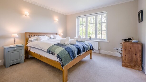 A bedroom with a wooden bed, bedside lamps, a window, and a wooden cabinet. - 3 Bed in Berwick St. John (oc-k36615) (Berwick Saint John)
