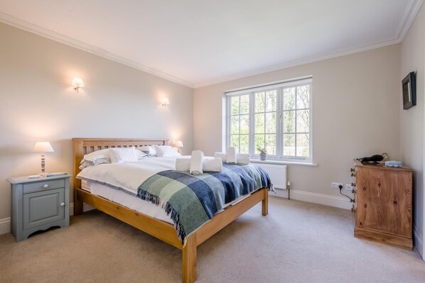 A bedroom with a wooden bed, bedside lamps, a window, and a wooden cabinet.